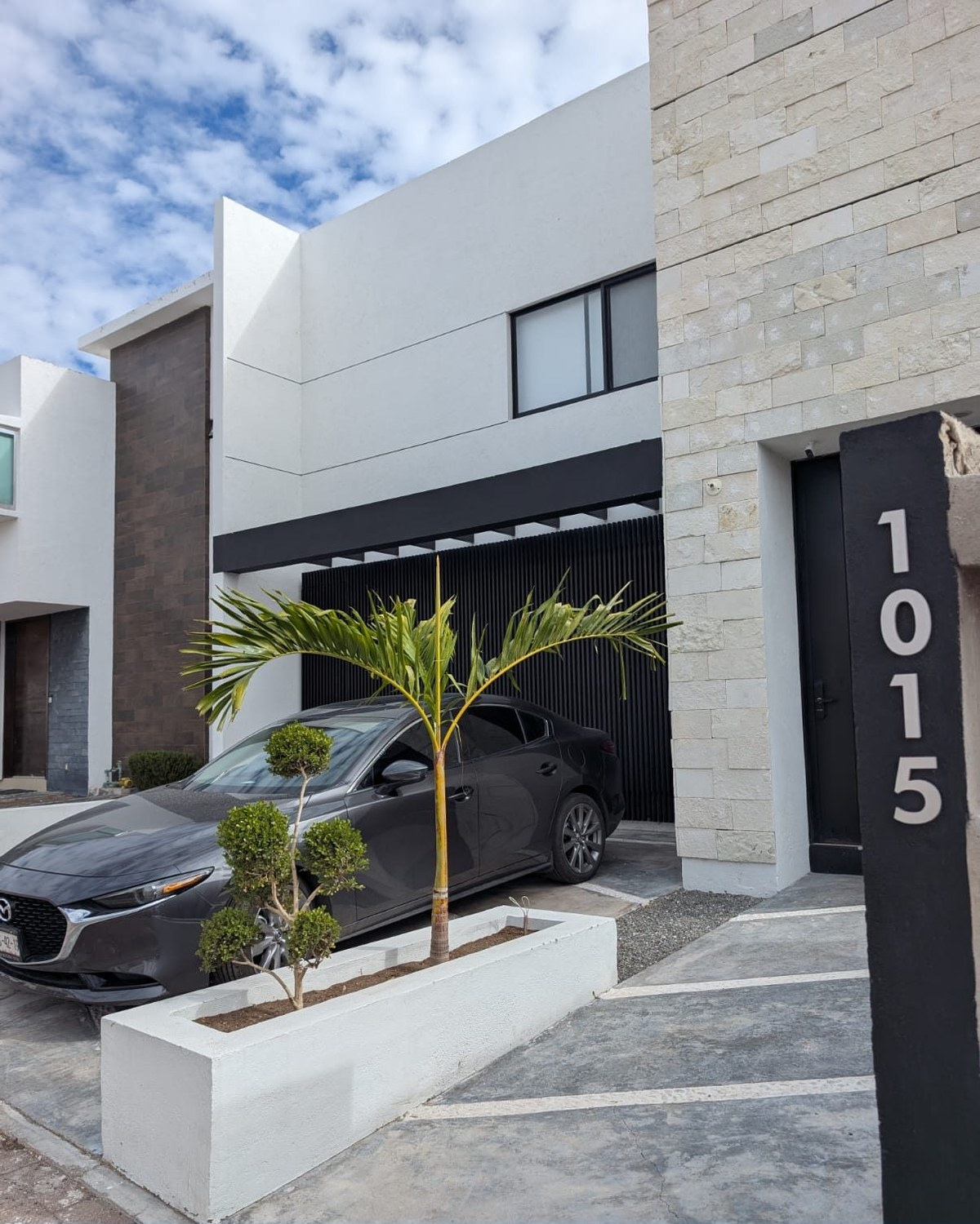 Casa Condesa 2 construida en Condesa Juriquilla, Querétaro: fachada blanca con paño de piedra natural y celosía negra — AVives Arquitectos