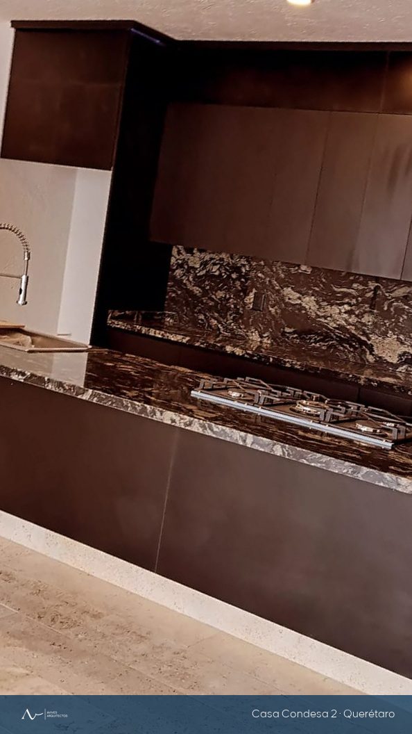 Cocina terminada con granito veteado, carpintería oscura y piso de travertino