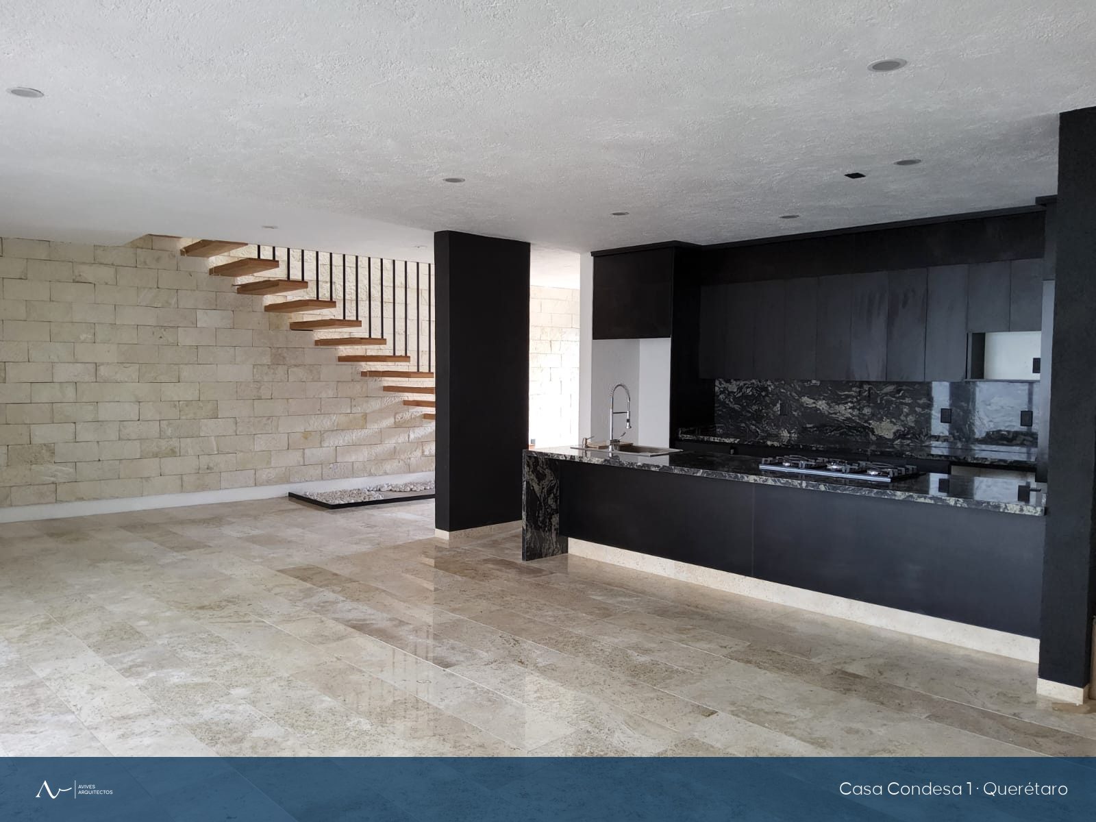 Estancia y cocina en granito negro de la casa, con la escalera al fondo