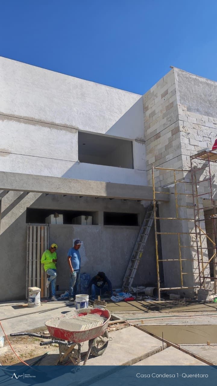 Fachada de la casa en construcción, con andamios y el equipo de obra
